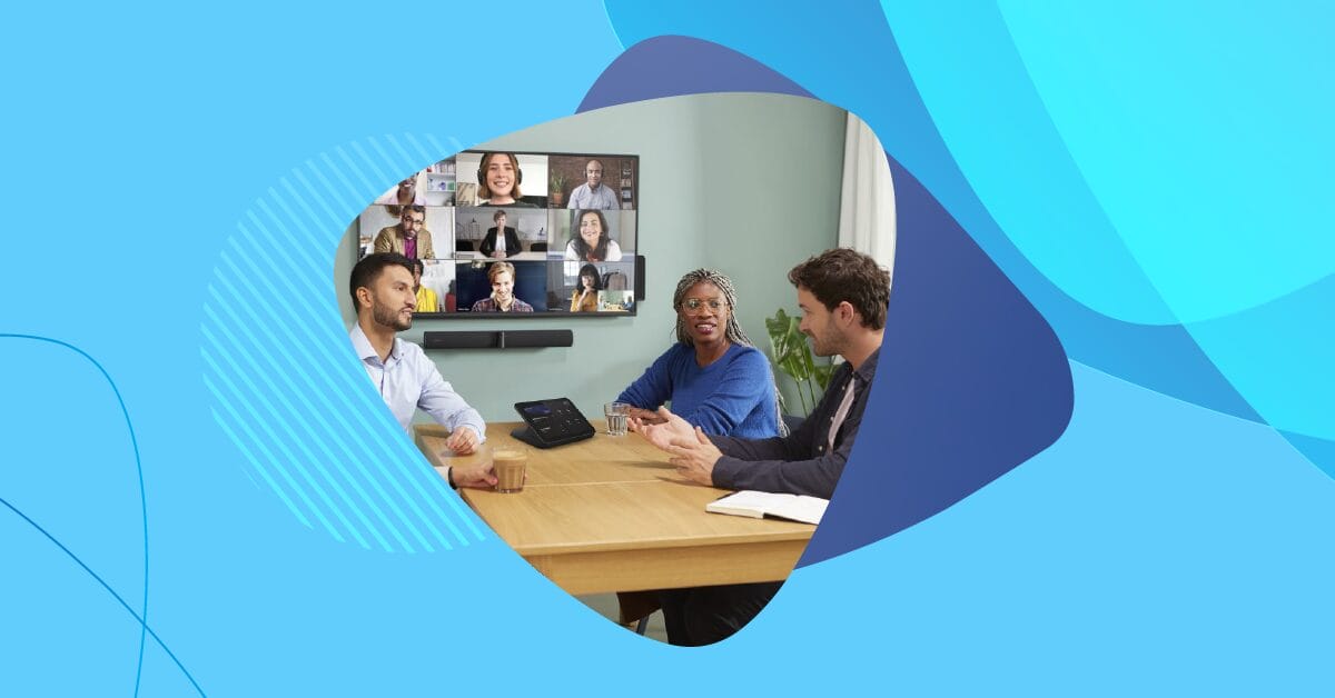 Three people in a Microsoft Teams Room meeting with a wall-mounted screen displaying remote participants.